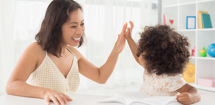 Mother and daughter high-fiving in a bright home, enjoying cool indoor air from a reliable air conditioning system